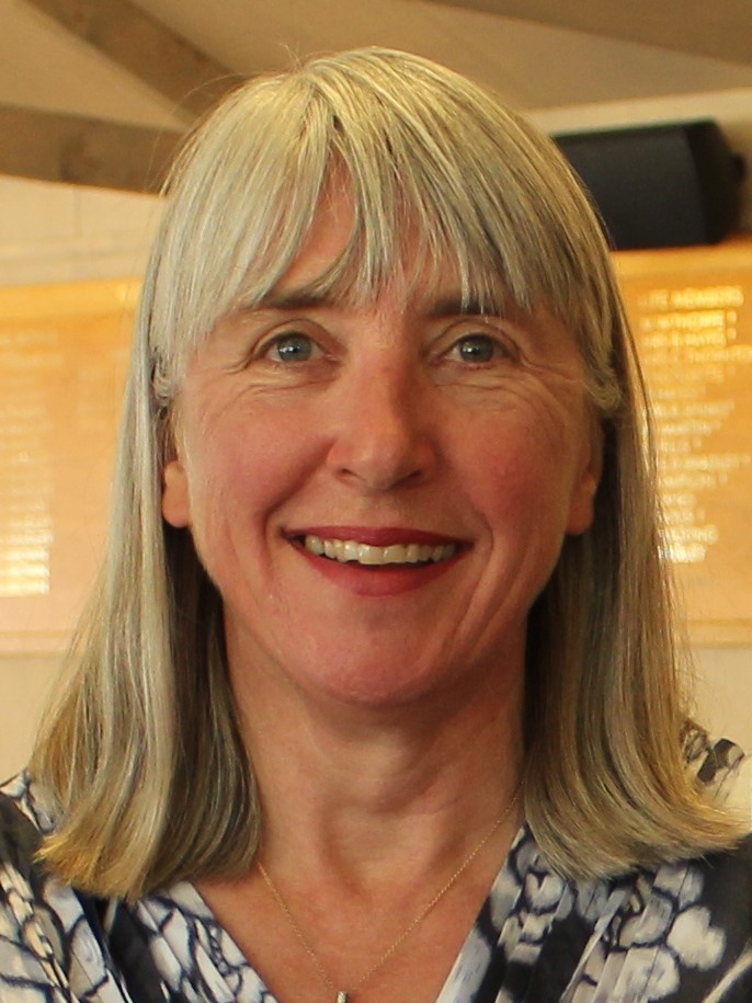 Smiling person with grey hair indoors.