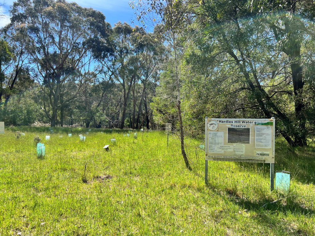 Hardies Hill Water Reserve sign in grassy area.