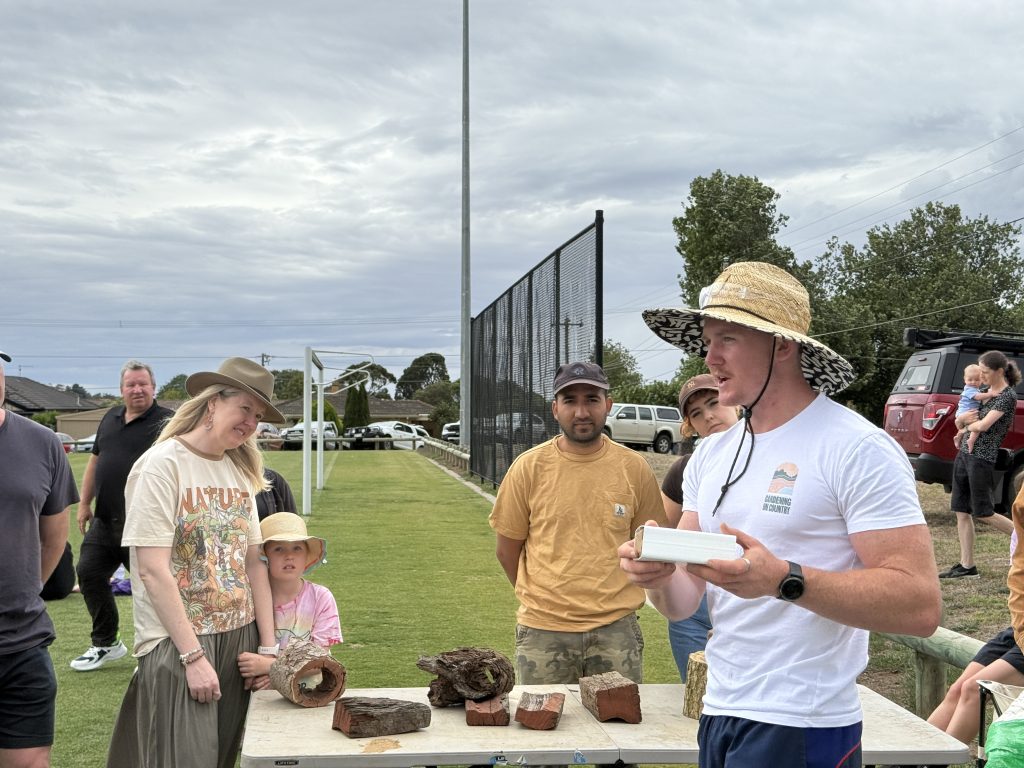 Group discussing outdoors with tree logs on table.