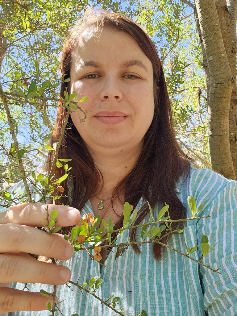 Person holding a tree branch outdoors.